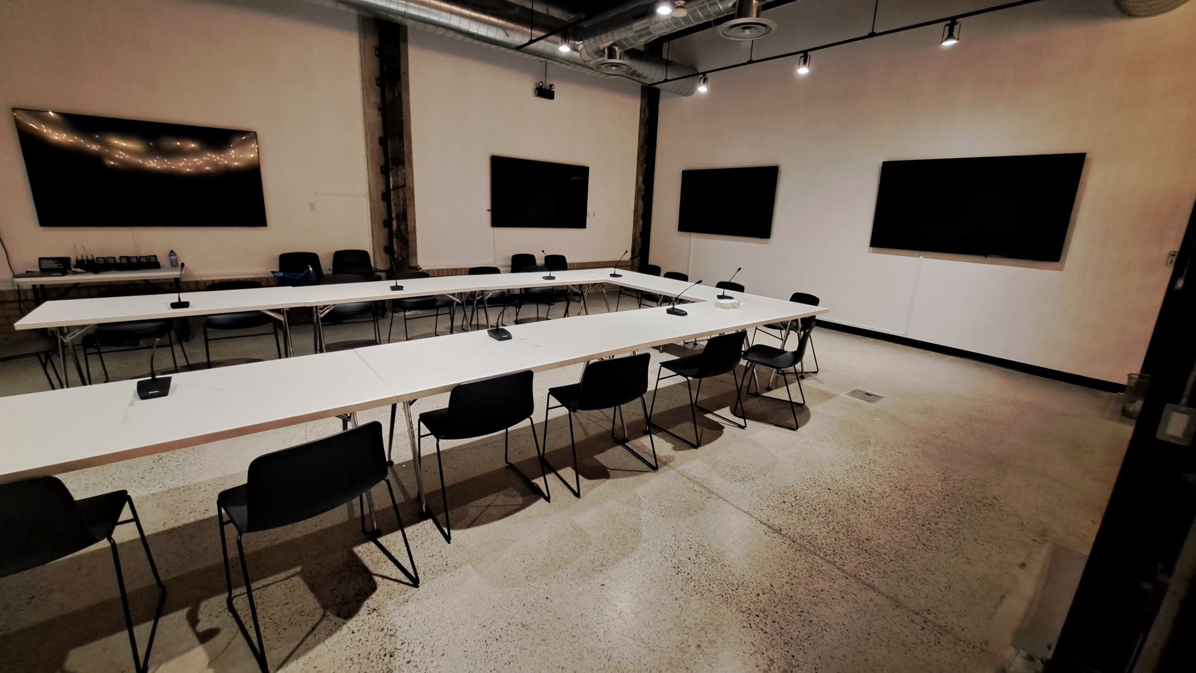 A meeting room with wall-mounted displays at the head of the table.